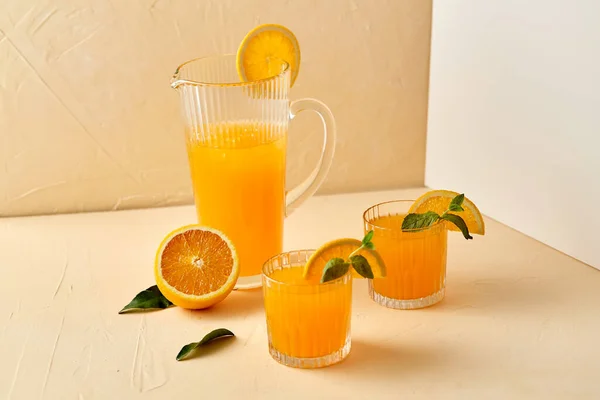 Glazen met sinaasappelsap en pepermunt op tafel — Stockfoto