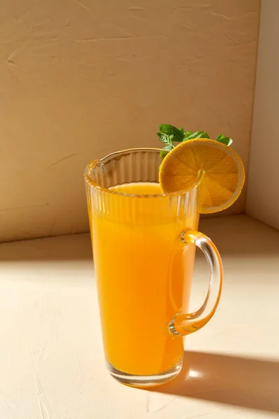 Jarra con zumo de naranja y menta en la mesa — Foto de Stock