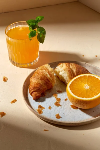 Стакан апельсинового сока и круассан на тарелке — стоковое фото