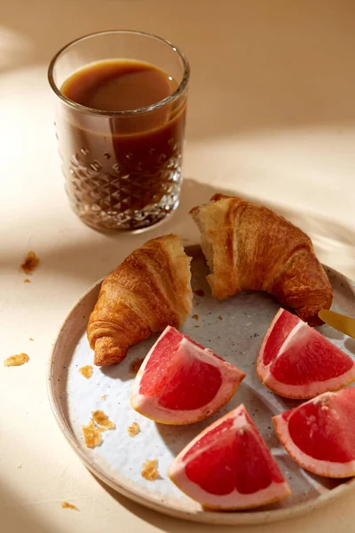 Verre de café, croissant et pamplemousse sur la table — Photo
