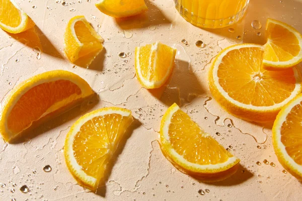 Vaso de jugo y rodajas de naranja sobre mesa húmeda —  Fotos de Stock