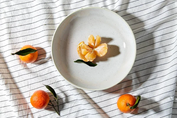 Still life with mandarins on plate over drapery — Stock Photo, Image