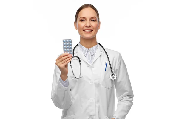 Sorridente médico feminino segurando pílulas de medicina — Fotografia de Stock