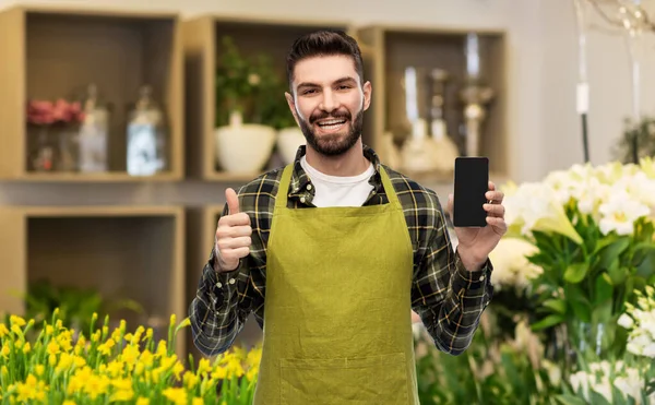 Sprzedawca z telefonem pokazuje kciuki w kwiaciarni — Zdjęcie stockowe