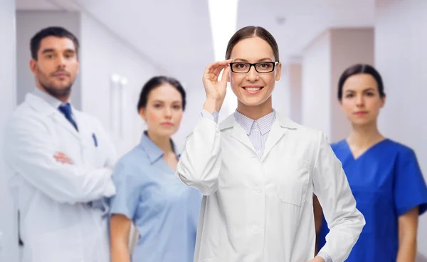 Sorridente médico feminino com colegas no hospital — Fotografia de Stock