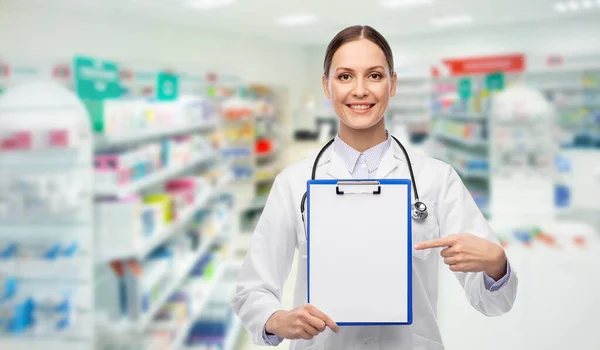 Feliz médico femenino con portapapeles en la farmacia —  Fotos de Stock