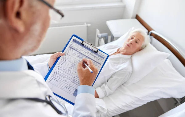 Idős nő és orvos írótáblával a kórházban — Stock Fotó