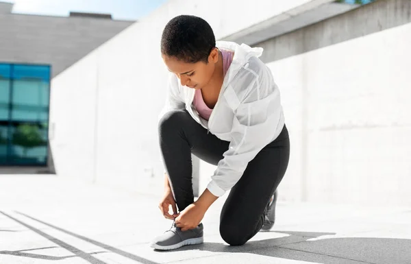 Africano americano mujer apretando zapatillas de deporte —  Fotos de Stock