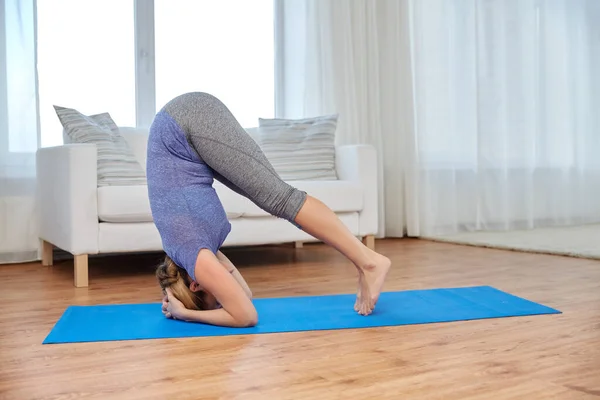 Vrouw maken yoga headstand pose op mat thuis — Stockfoto