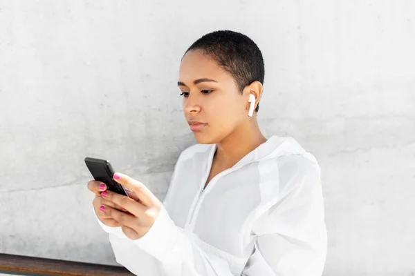 Africká americká žena se sluchátky a telefonem — Stock fotografie