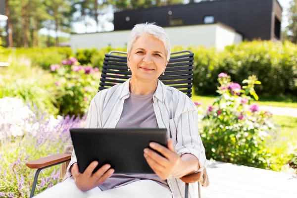 Mujer mayor feliz con la tableta PC en el jardín de verano —  Fotos de Stock