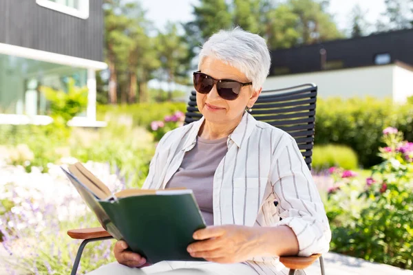 Glückliche Seniorin liest Buch im Sommergarten — Stockfoto