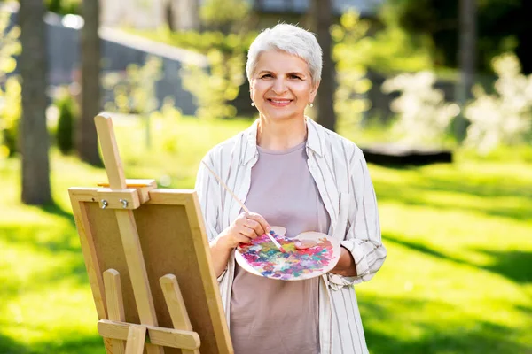 Старша жінка з мольбертовим живописом на відкритому повітрі — стокове фото
