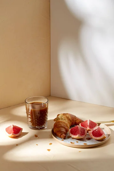 Verre de café, croissant et pamplemousse sur la table — Photo