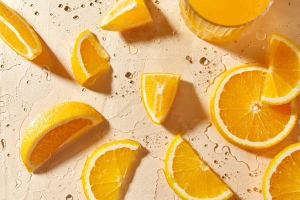 Glass of juice and orange slices on wet table — Stock Photo, Image