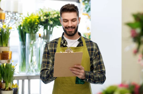 Happy male seller with clipboard at flower shop — Stock Photo, Image