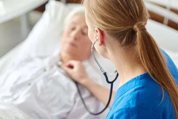 Médico com estetoscópio e mulher idosa no hospital — Fotografia de Stock