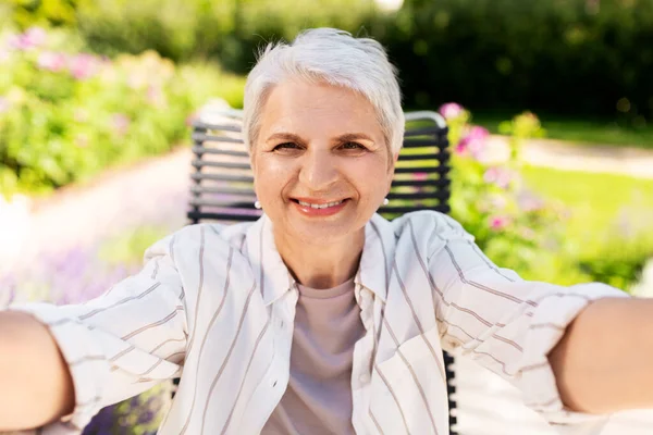 Χαρούμενη ηλικιωμένη γυναίκα που βγάζει selfie στον καλοκαιρινό κήπο — Φωτογραφία Αρχείου