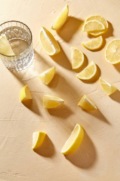 Egy pohár víz és citromszeletek az asztalon — Stock Fotó