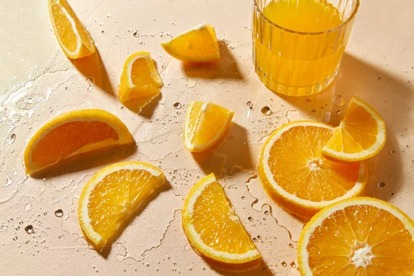 Glas Saft und Orangenscheiben auf nassem Tisch — Stockfoto