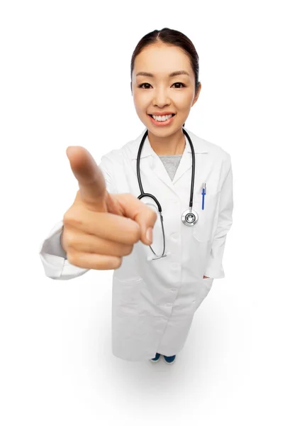 Счастливая азиатка-врач, указывающая на камеру — стоковое фото