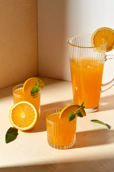 Copos com suco de laranja e hortelã-pimenta na mesa Fotos De Bancos De Imagens