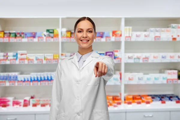 Farmacêutico feminino apontando para câmera na farmácia — Fotografia de Stock