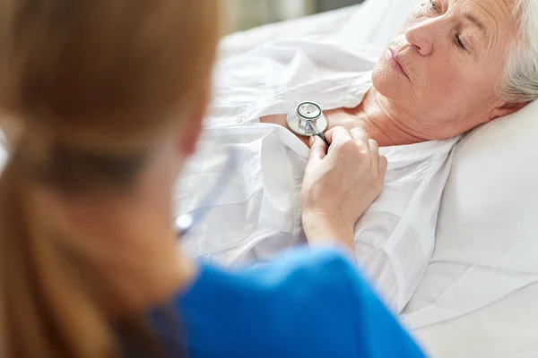 Steteskoplu bir doktor ve hastanede yaşlı bir kadın. — Stok fotoğraf