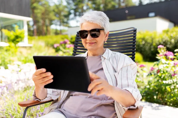 Szczęśliwa seniorka z tabletem w ogrodzie letnim — Zdjęcie stockowe