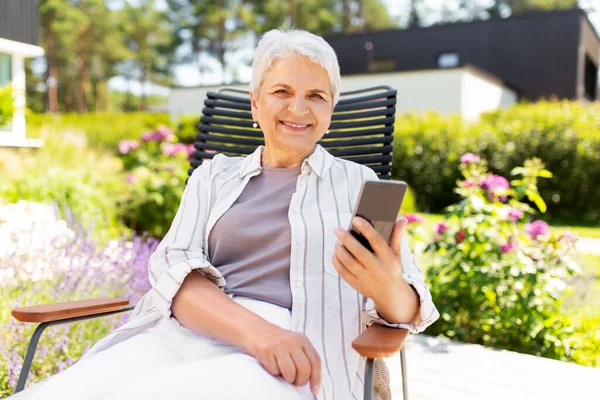 Szczęśliwa starsza kobieta z telefonem w ogrodzie letnim — Zdjęcie stockowe