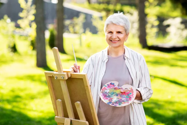 Mulher idosa com cavalete pintura ao ar livre — Fotografia de Stock