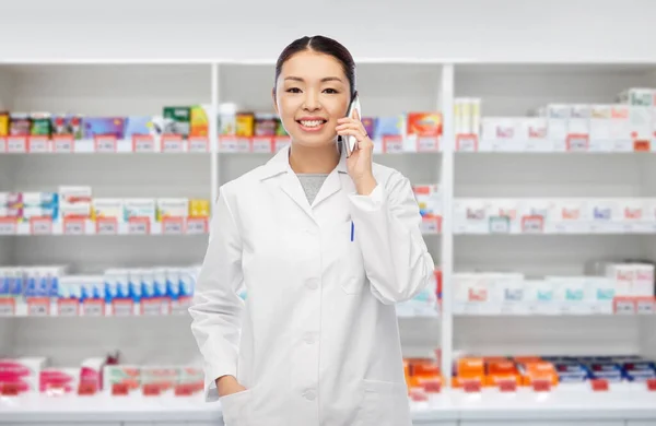 Farmacéutico asiático llamando por teléfono en la farmacia — Foto de Stock