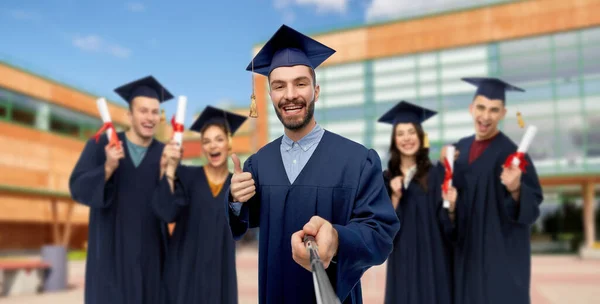 Estudiante de posgrado masculino tomando selfie con monópodo — Foto de Stock