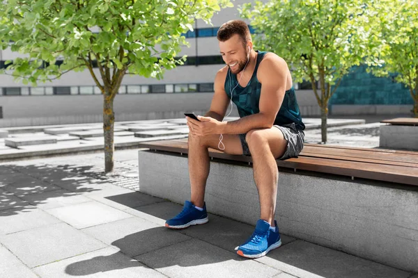 Joven atleta hombre con auriculares y teléfono inteligente —  Fotos de Stock