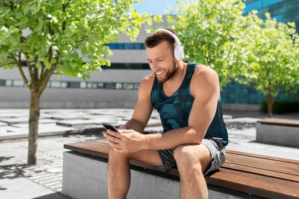 Kulaklığı ve akıllı telefonu olan genç bir atlet. — Stok fotoğraf