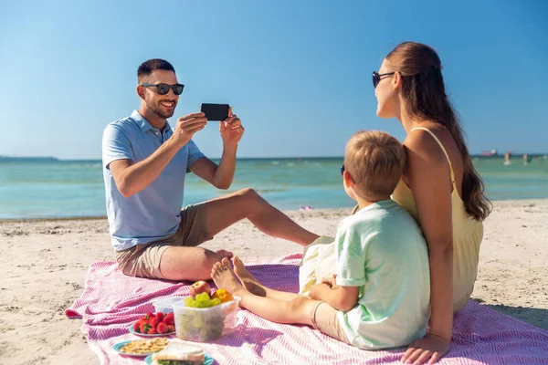 Familie med smarttelefon fotografering på stranden – stockfoto