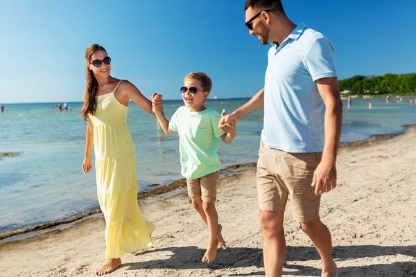 Famille heureuse marchant le long de la plage d'été — Photo