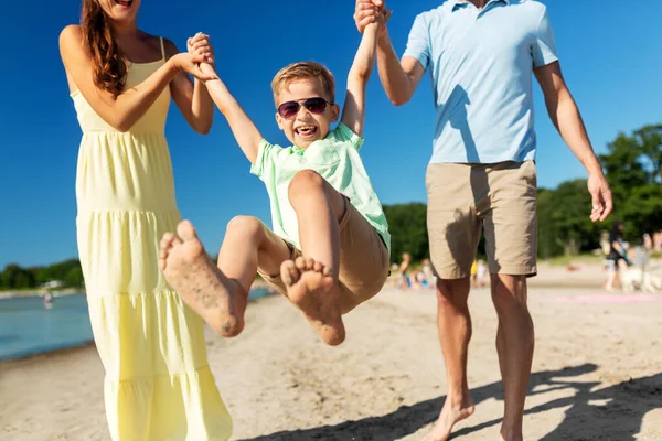 Familia feliz caminando a lo largo de la playa de verano — Foto de Stock