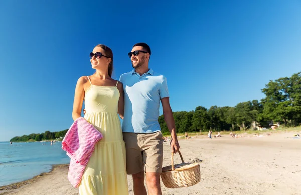 Szczęśliwa para z koszykiem piknikowym spacerująca po plaży — Zdjęcie stockowe