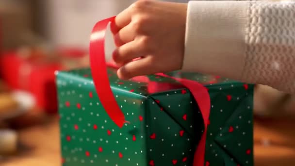 Hands packing christmas gift and tying bow — Stock Video