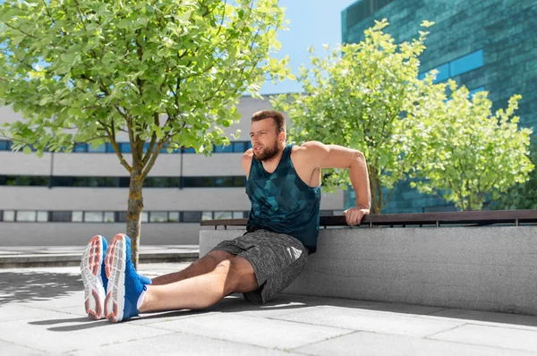 Young man doing triceps dip on city street — Stock Photo, Image