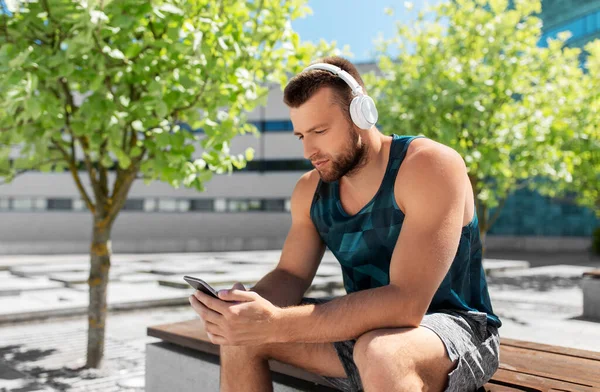 Joven atleta hombre con auriculares y teléfono inteligente —  Fotos de Stock