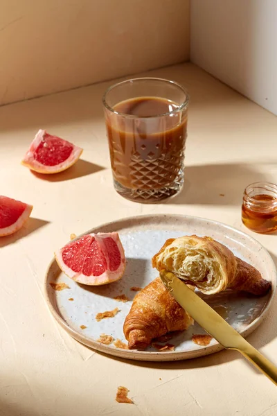 Glas Kaffee, Croissant und Grapefruit auf dem Tisch — Stockfoto