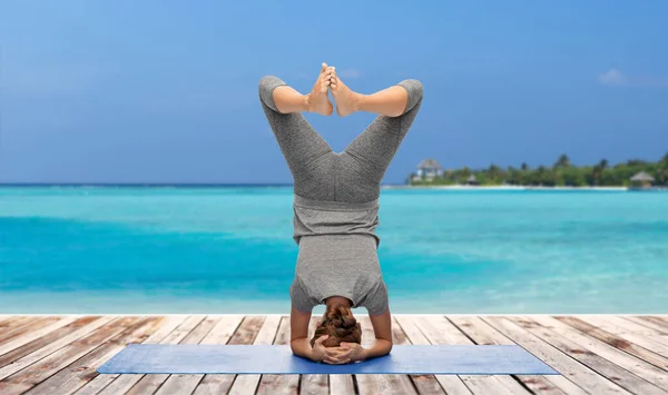 Frau macht Yoga im Kopfstand über Ozean — Stockfoto