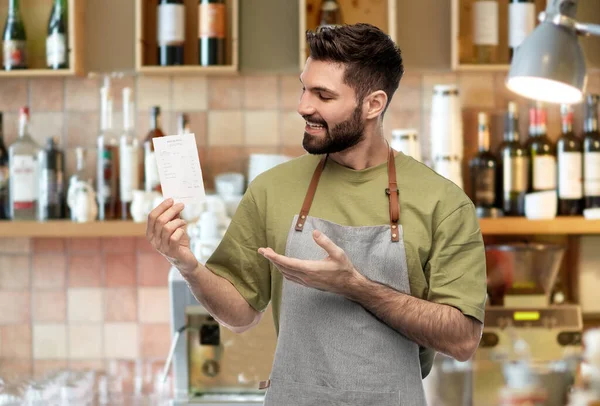 Feliz barman sonriente en delantal con factura en el bar —  Fotos de Stock