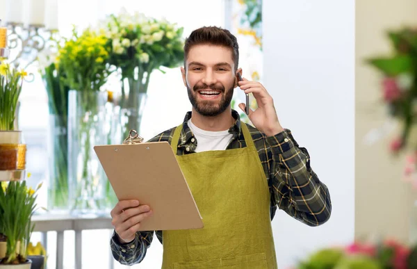 Jardineiro masculino com prancheta chamando no smartphone — Fotografia de Stock