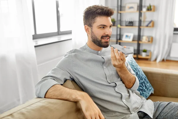 Hombre feliz con voz de grabación de teléfonos inteligentes en casa —  Fotos de Stock