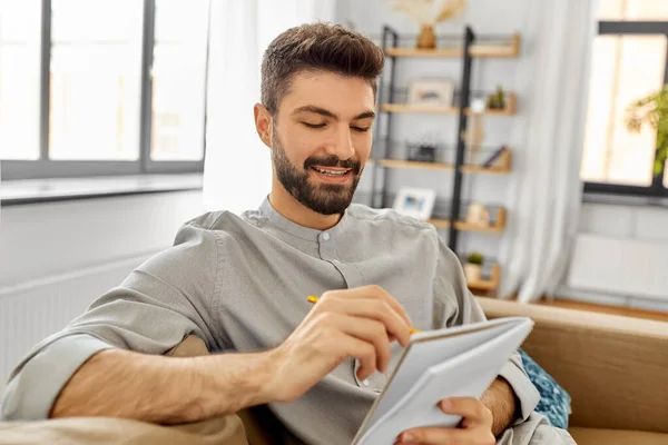 Homem escrevendo para notebook beber café em casa — Fotografia de Stock