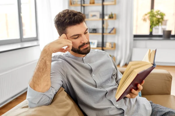 Adam evde kitap okuyor. — Stok fotoğraf