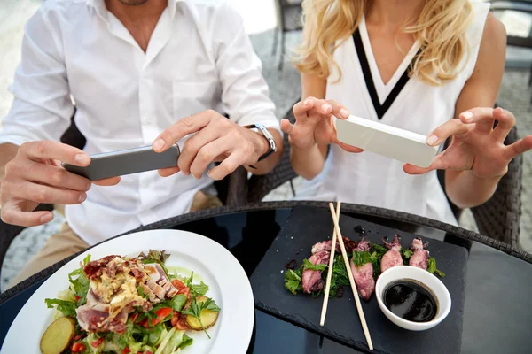 Par med smatphones fotografering mat — Stockfoto